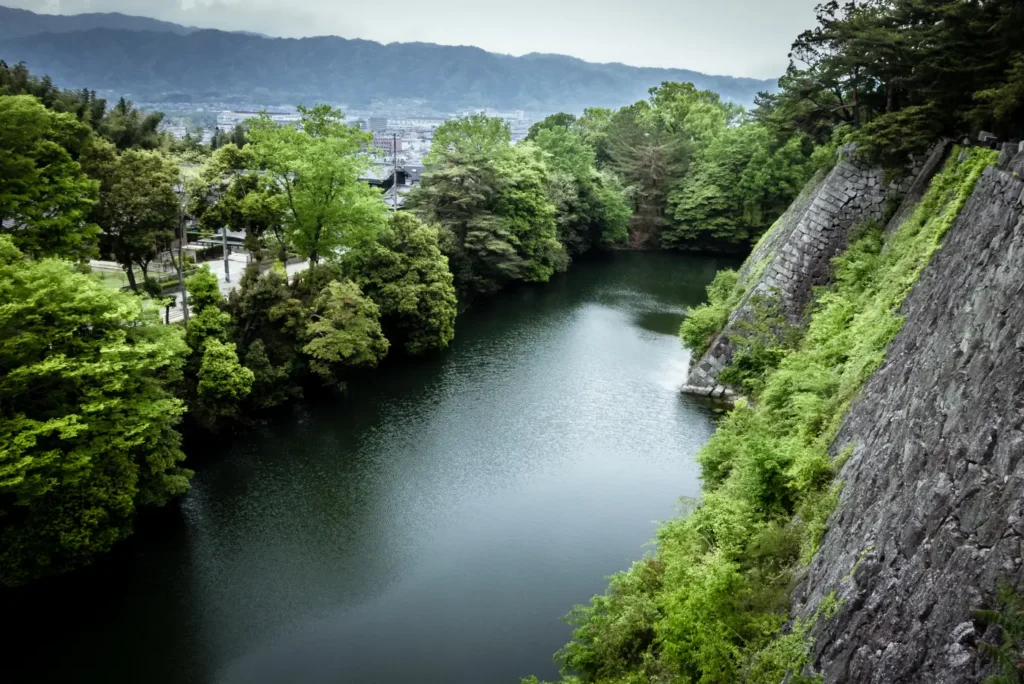 La haute muraille de pierre du château d’Iga Ueno, au-dessus des douves, dans la verdure